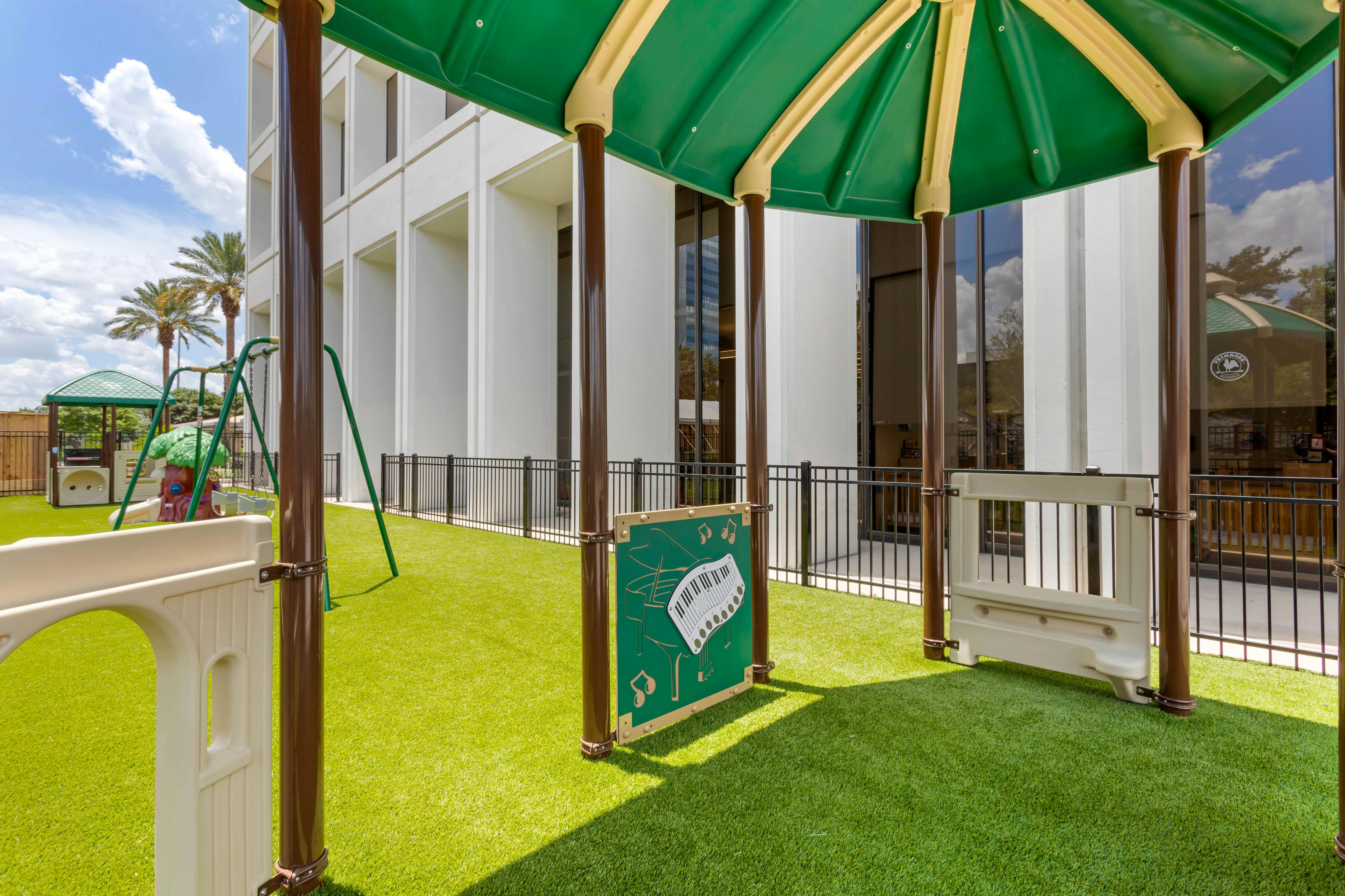Playground with green turf, a swing set, and a piano activity panel