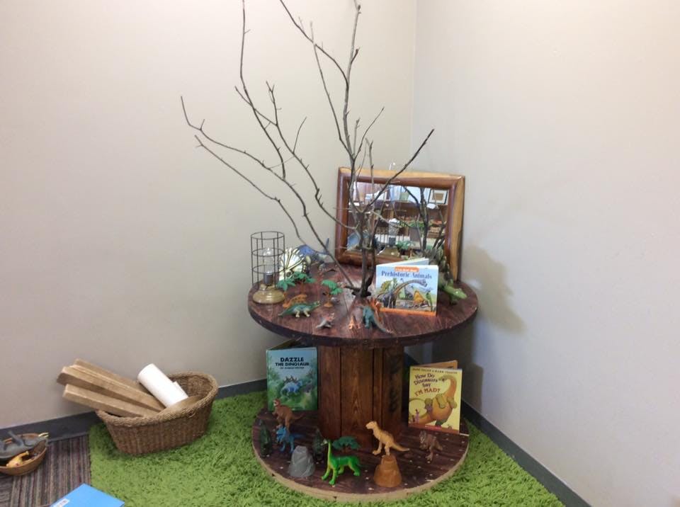 Table with dinosaur toys, books, and branches