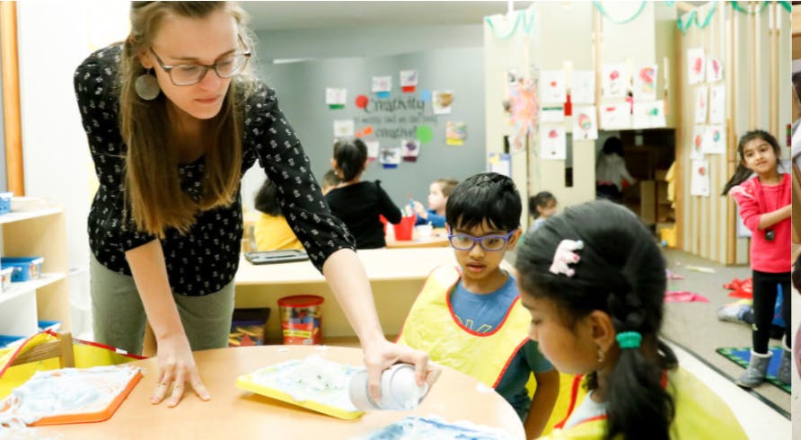 Adult and two children at a table in a classroom