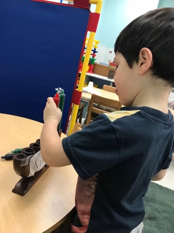 Child placing candles in a menorah