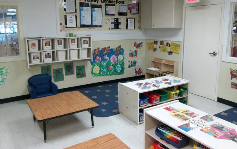 A classroom with child-sized tables, shelves, and artwork on the walls