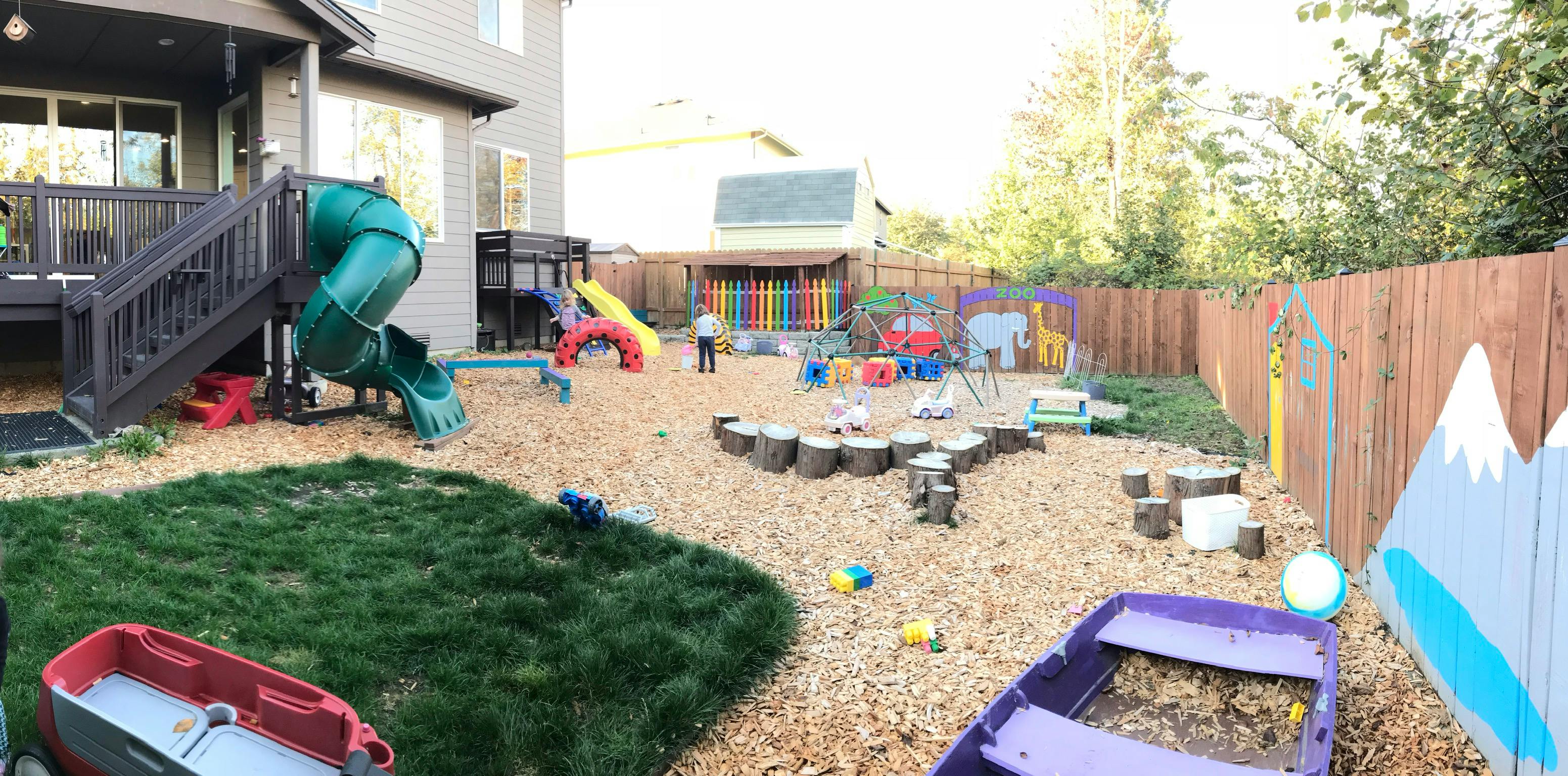 Backyard playground with slides, swings, and wood chips