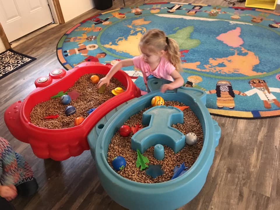 Child playing with toys in a sensory table