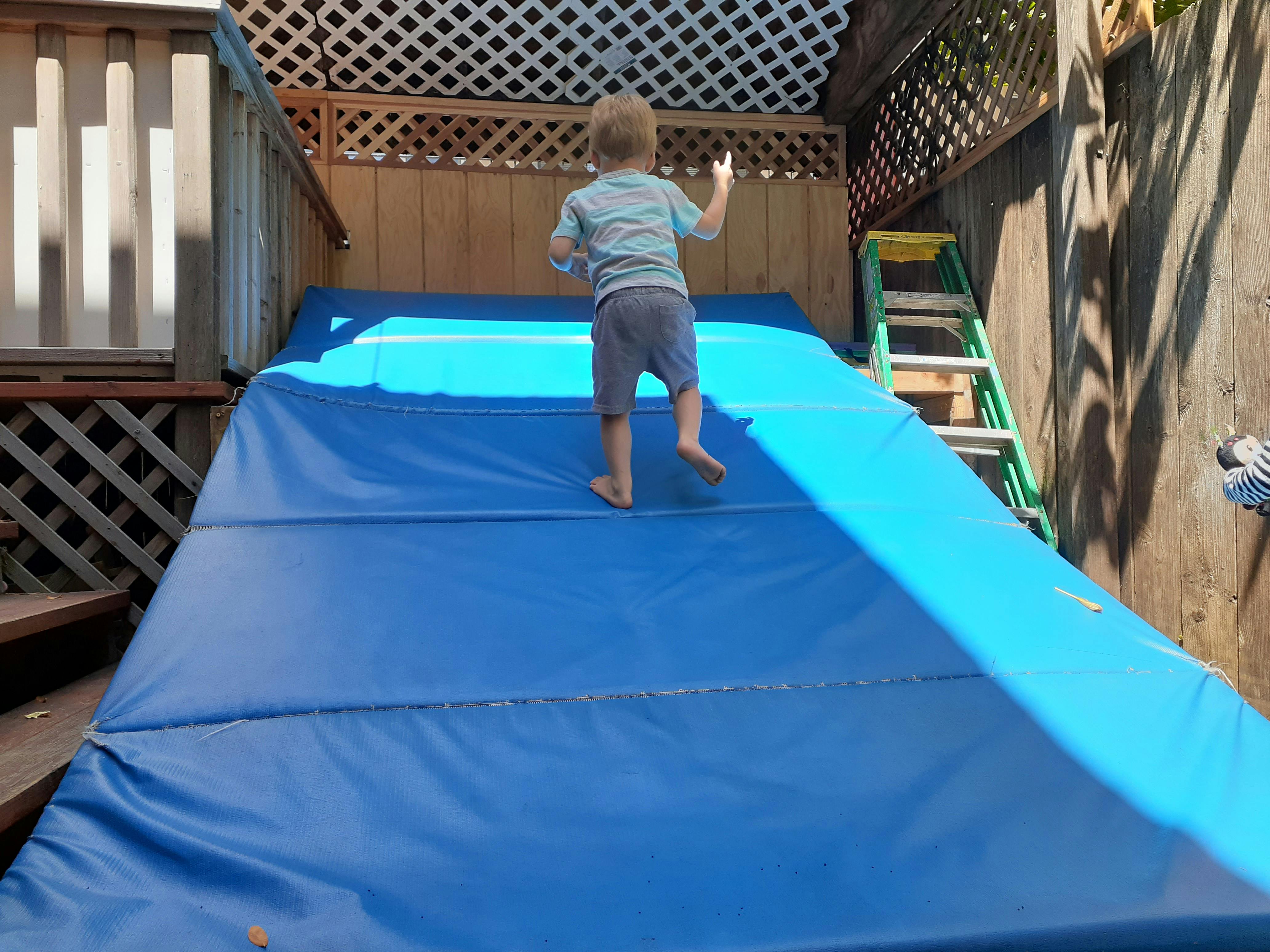Child walking up a blue mat ramp