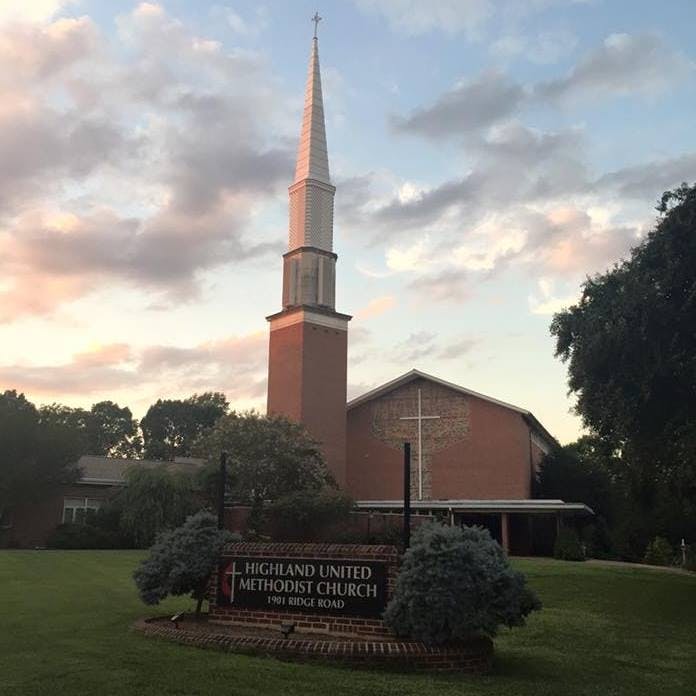 Church building with a tall steeple and a sign for Highland United Methodist Church