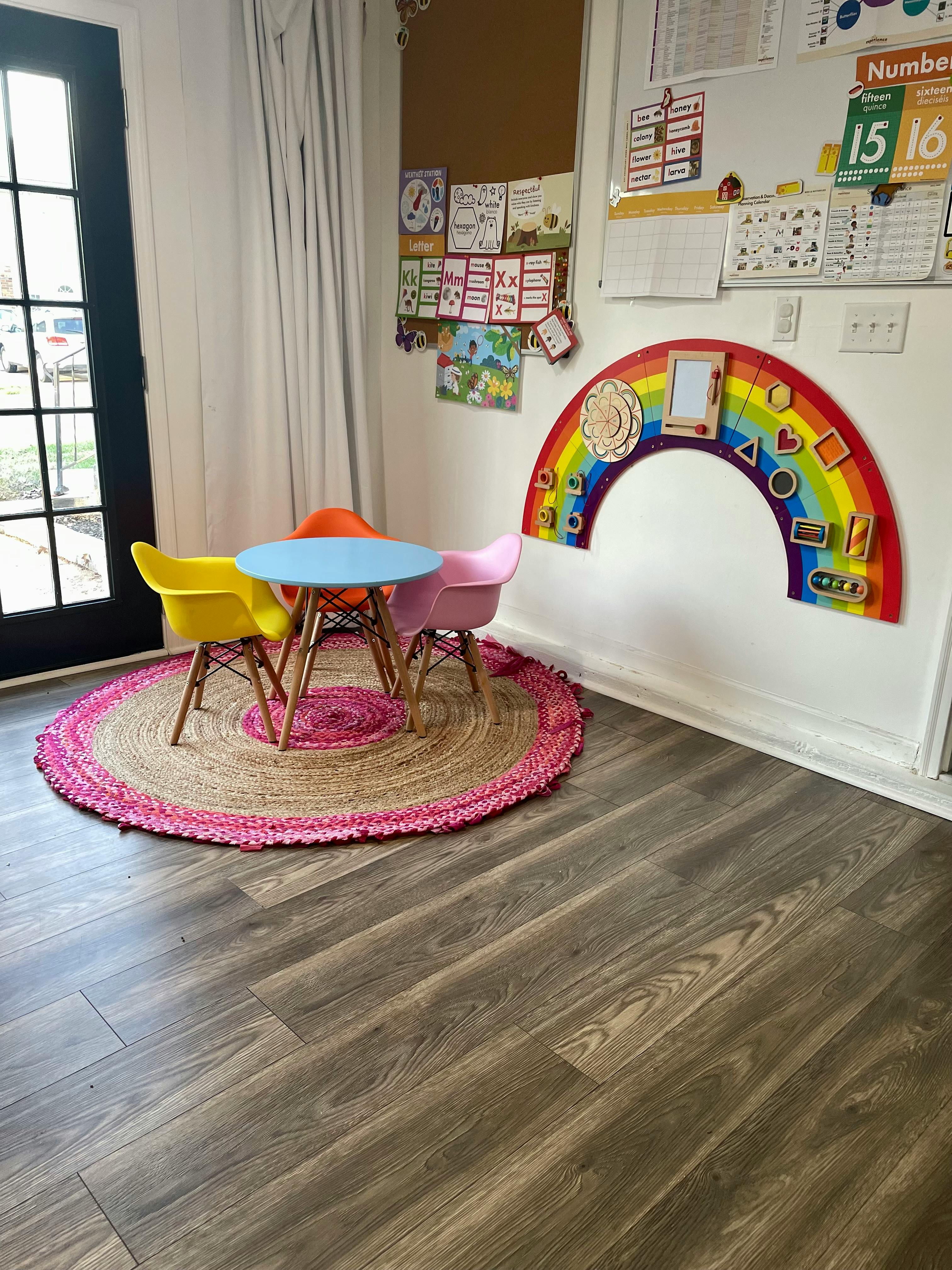 Children's play area with small table and chairs, rainbow activity board