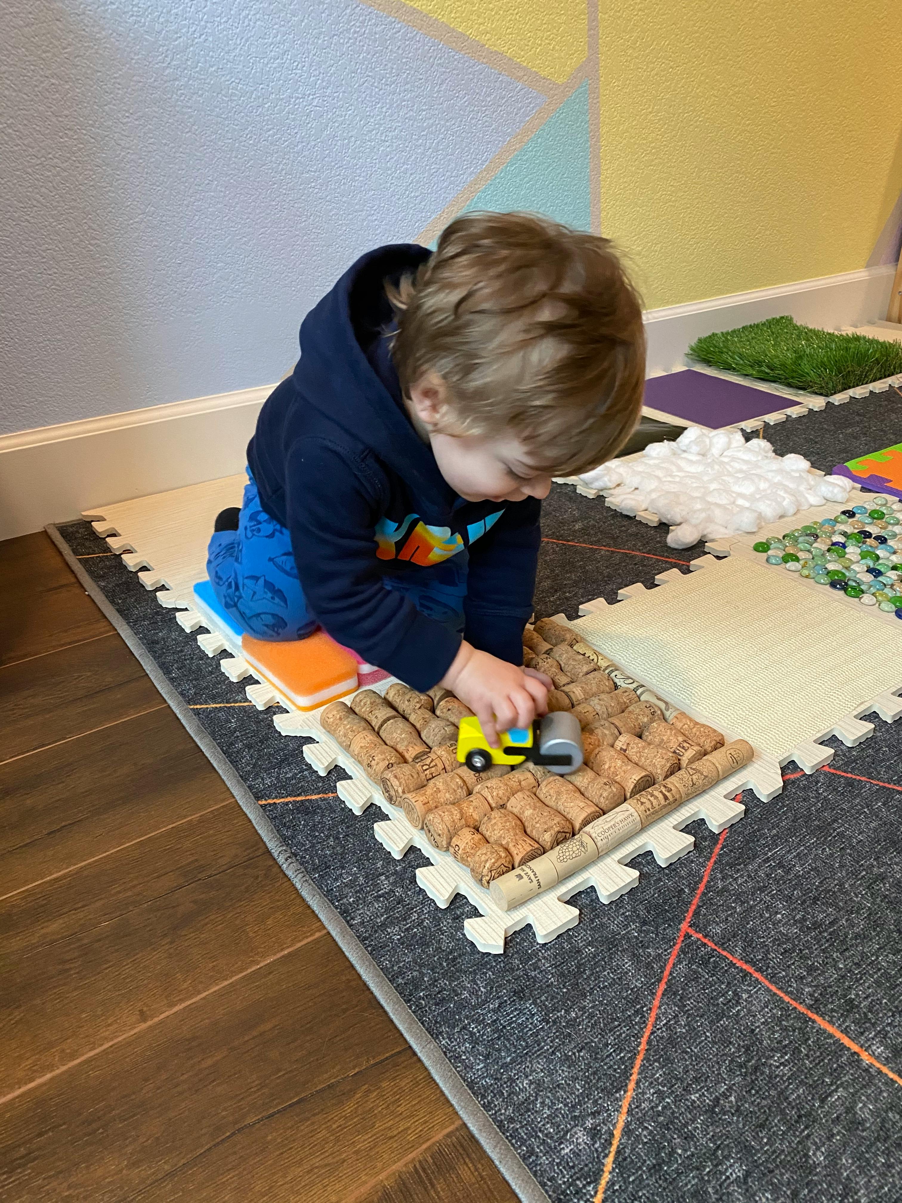 Child playing with a toy truck on a textured mat
