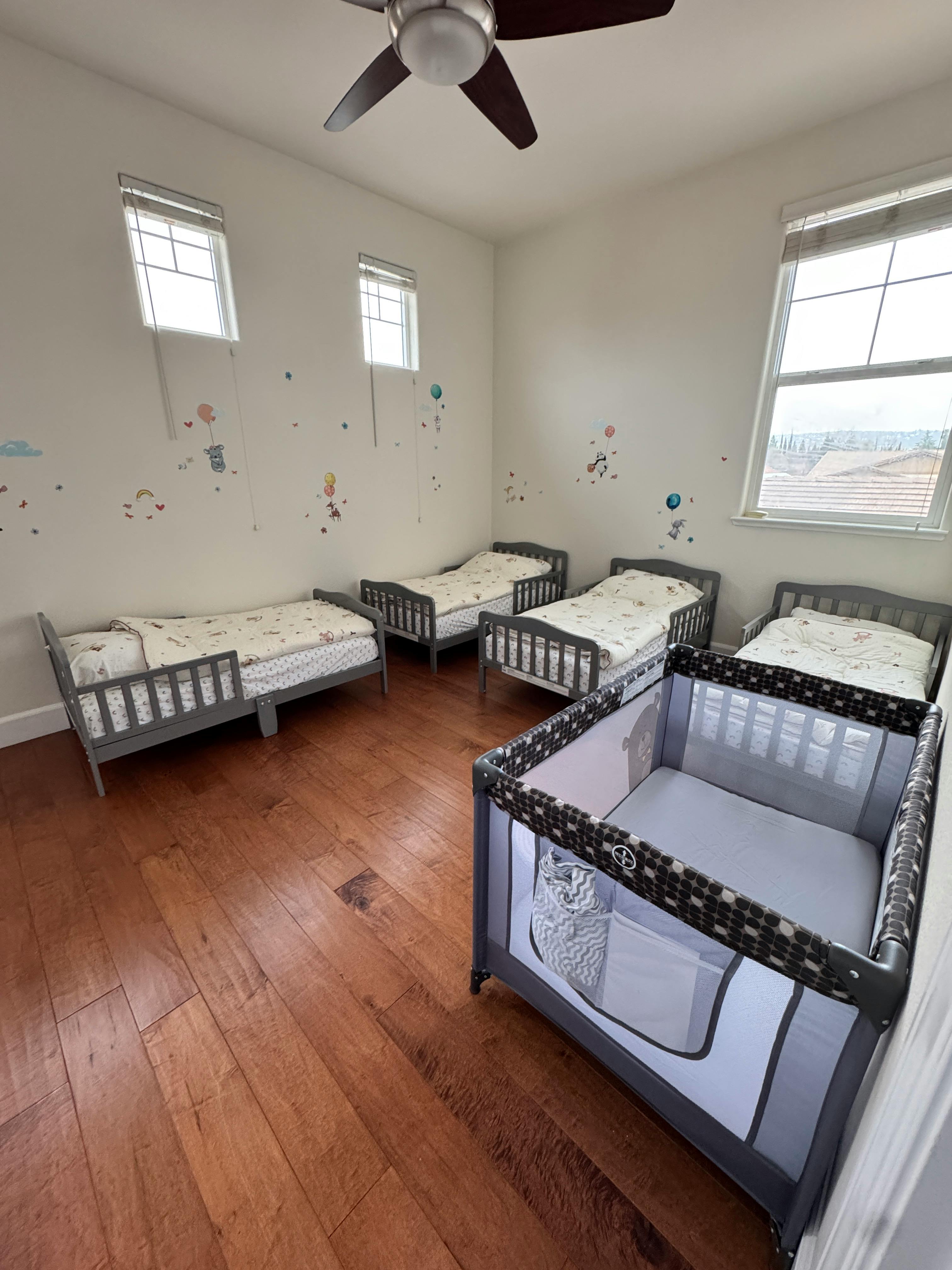 Room with multiple toddler beds and a playpen