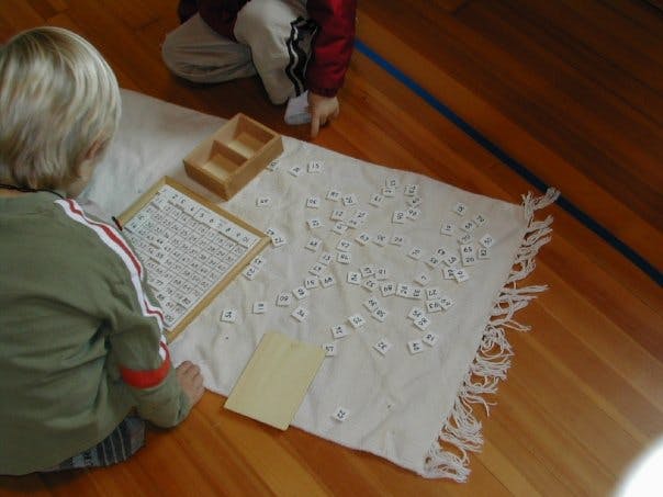 Child on floor with alphabet letters and a wooden frame with numbers