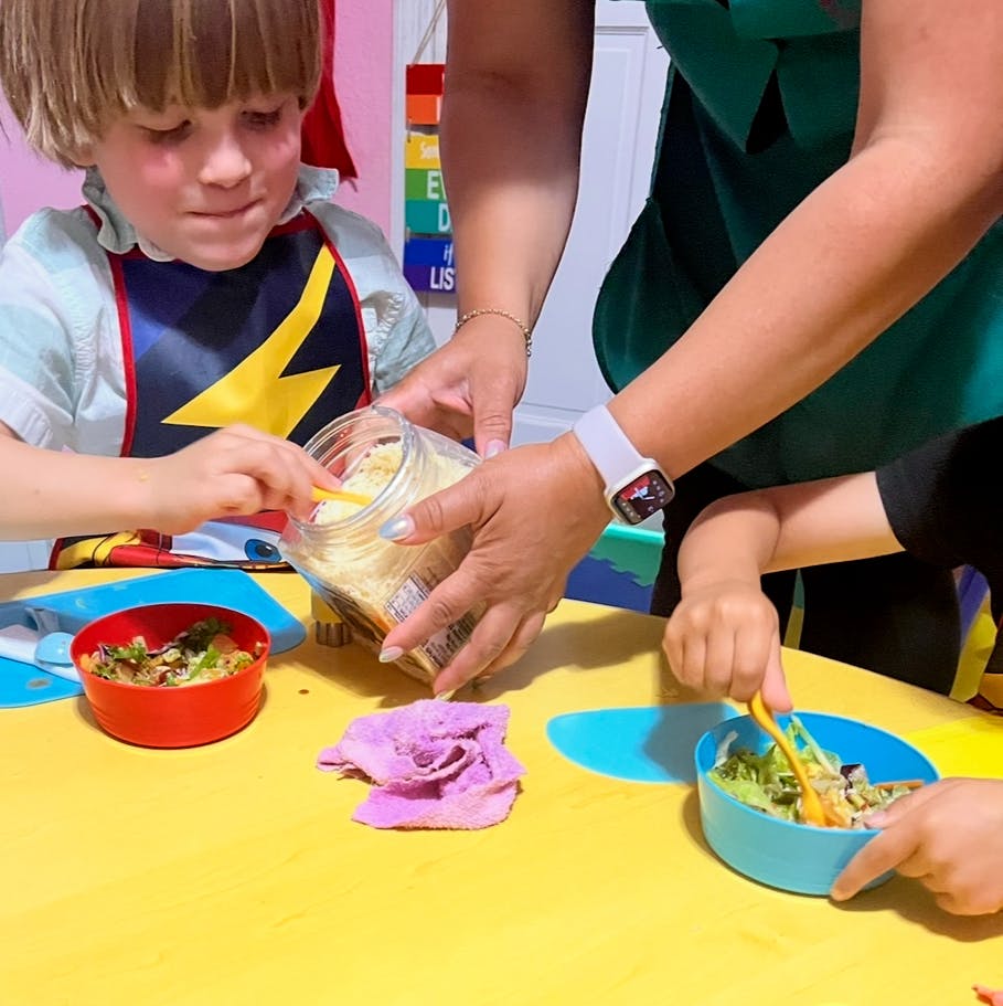Adult and children preparing food at a table