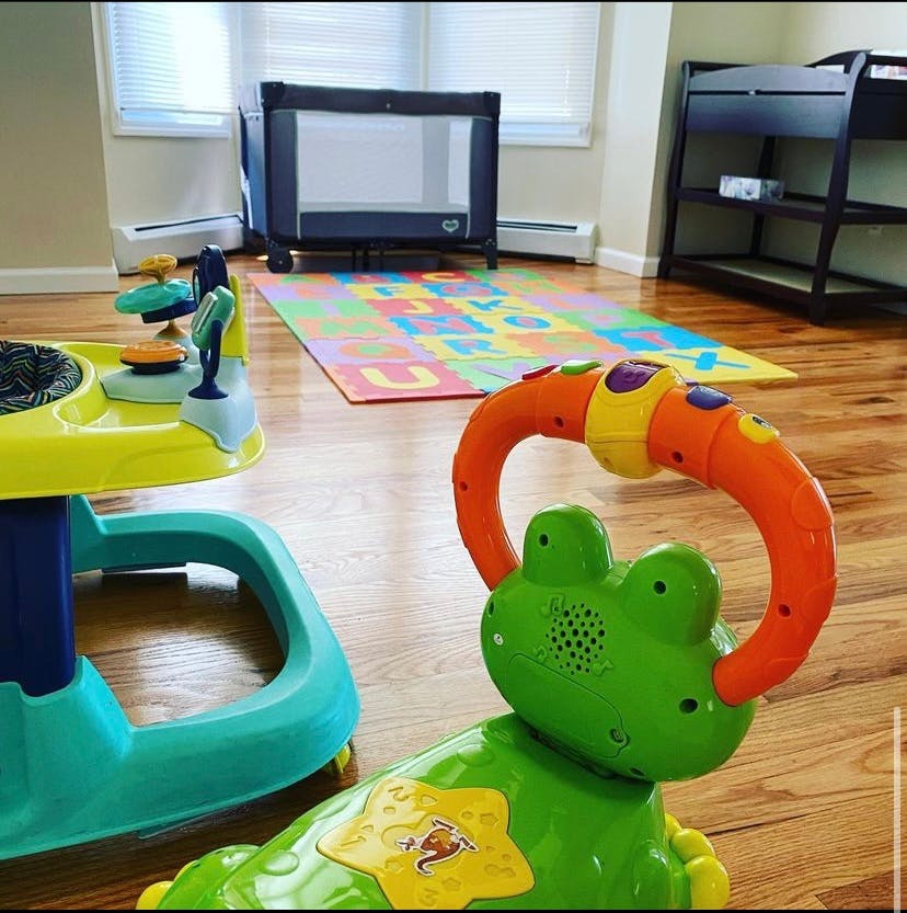 Playroom with baby toys, play mat, and crib