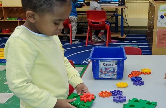 Child playing with interlocking gear toys at a table
