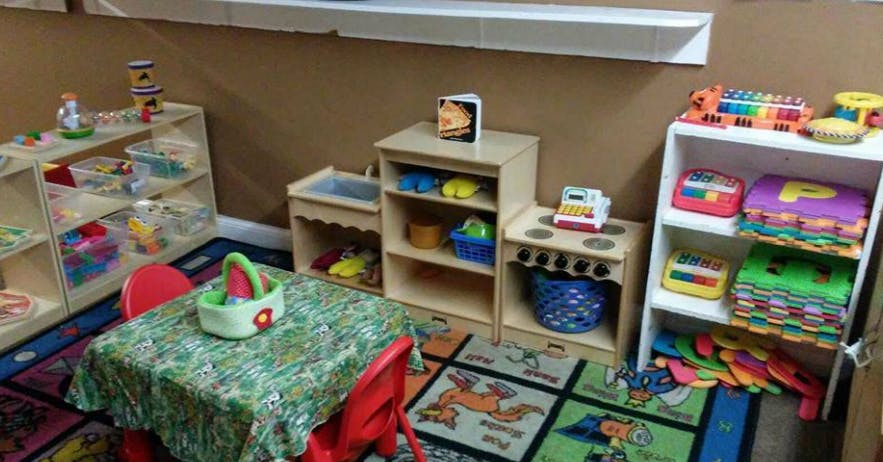 Playroom with small table and chairs, shelves with toys, and play kitchen