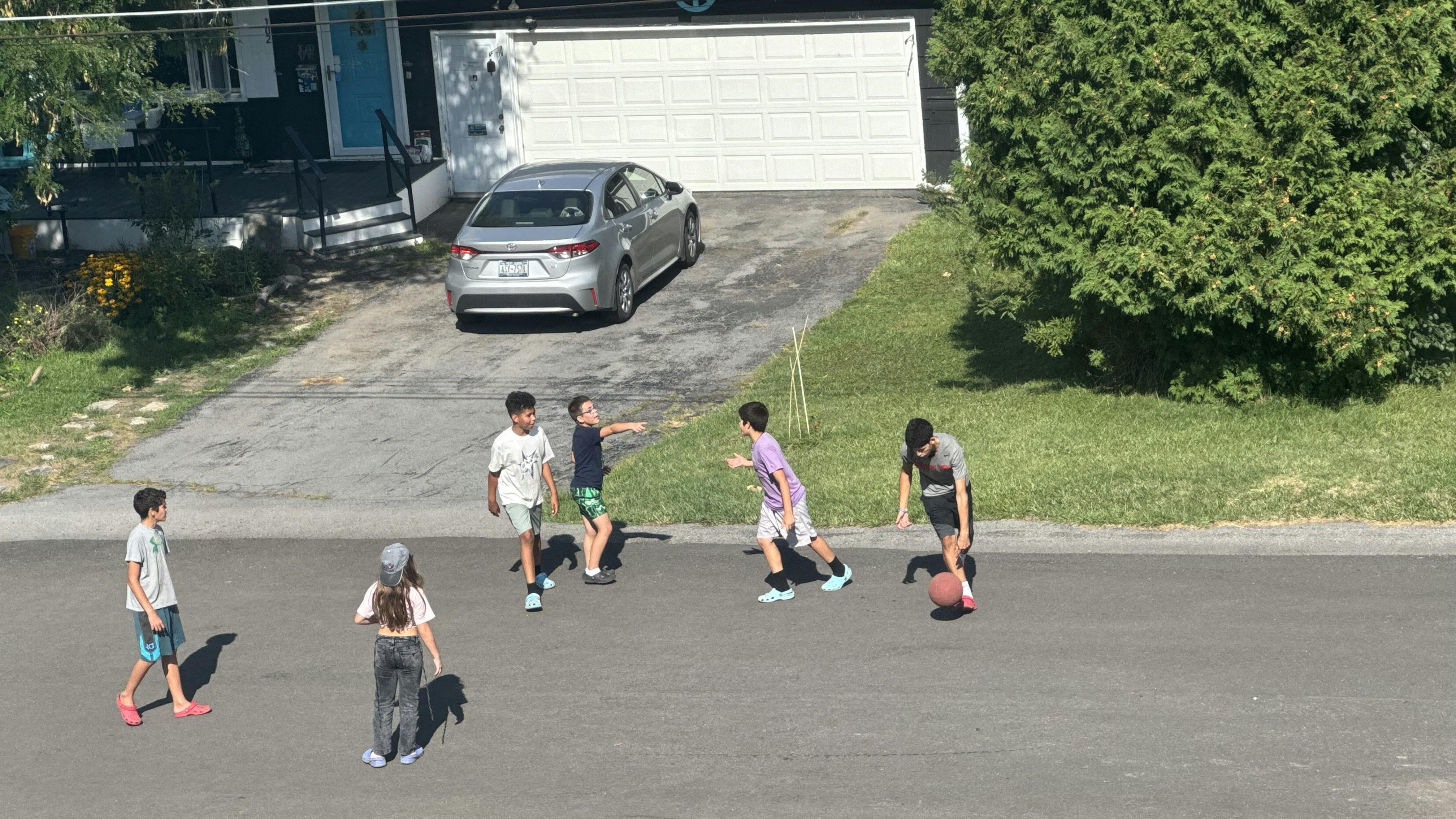 Group of children playing basketball in a driveway