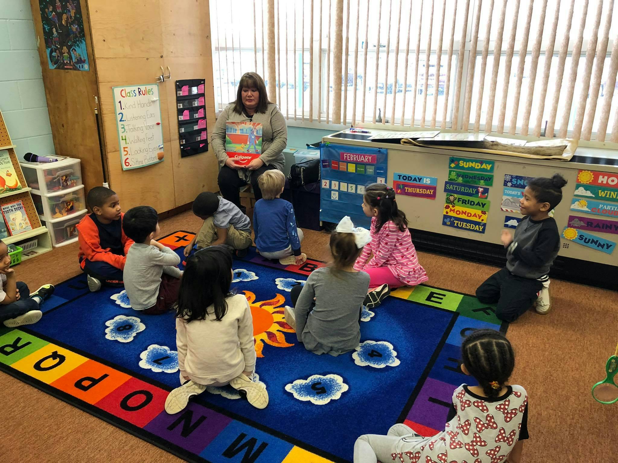 Adult reading to children sitting on a rug in a classroom