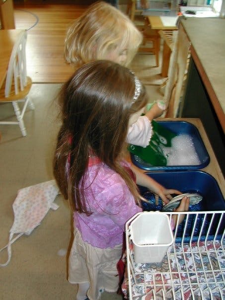 Child washing dishes in a classroom setting
