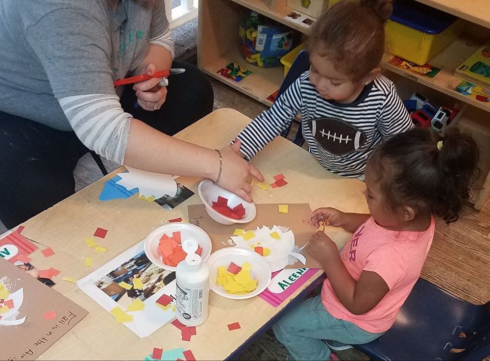 Person and two children doing crafts at a table