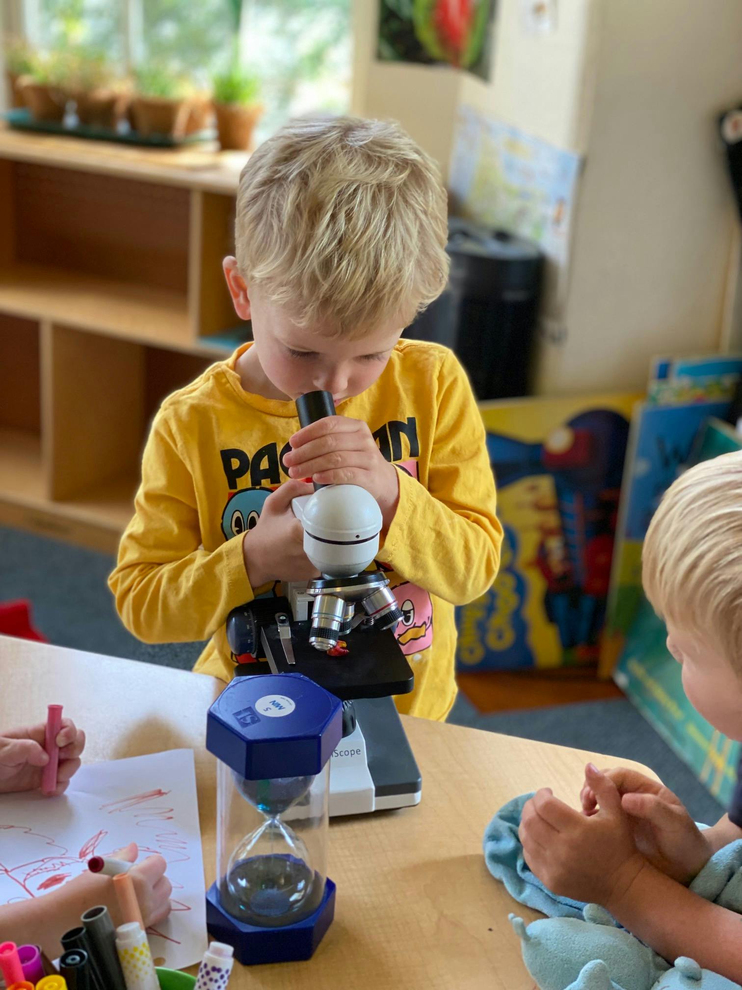 Child looking into a microscope in a classroom