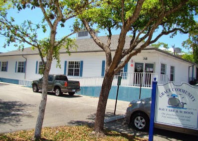 White building with blue trim and a sign for Grace Community Day Care & School