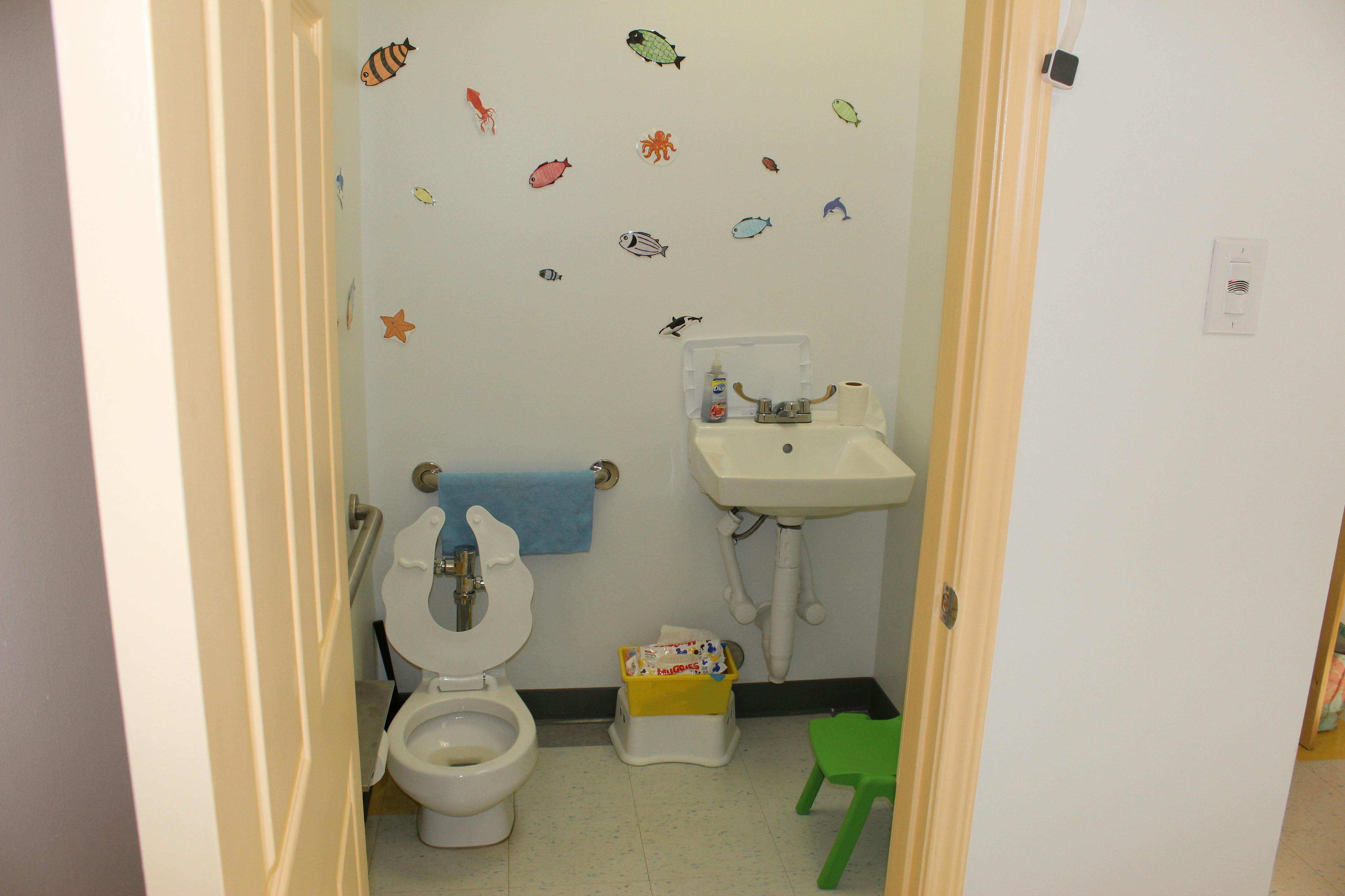 Small bathroom with toilet, sink, and fish decals on the wall