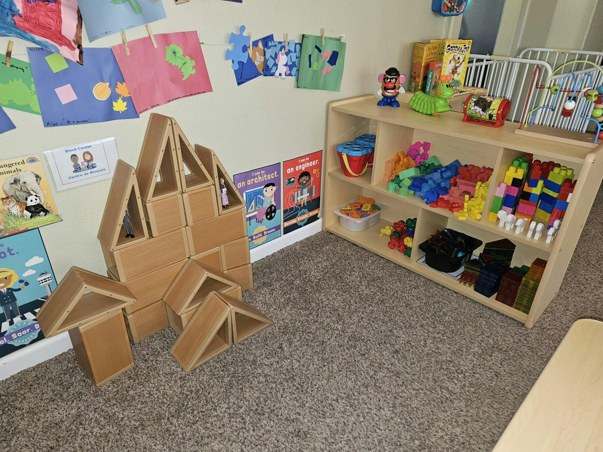 Wooden block structure and shelves filled with toys in a classroom