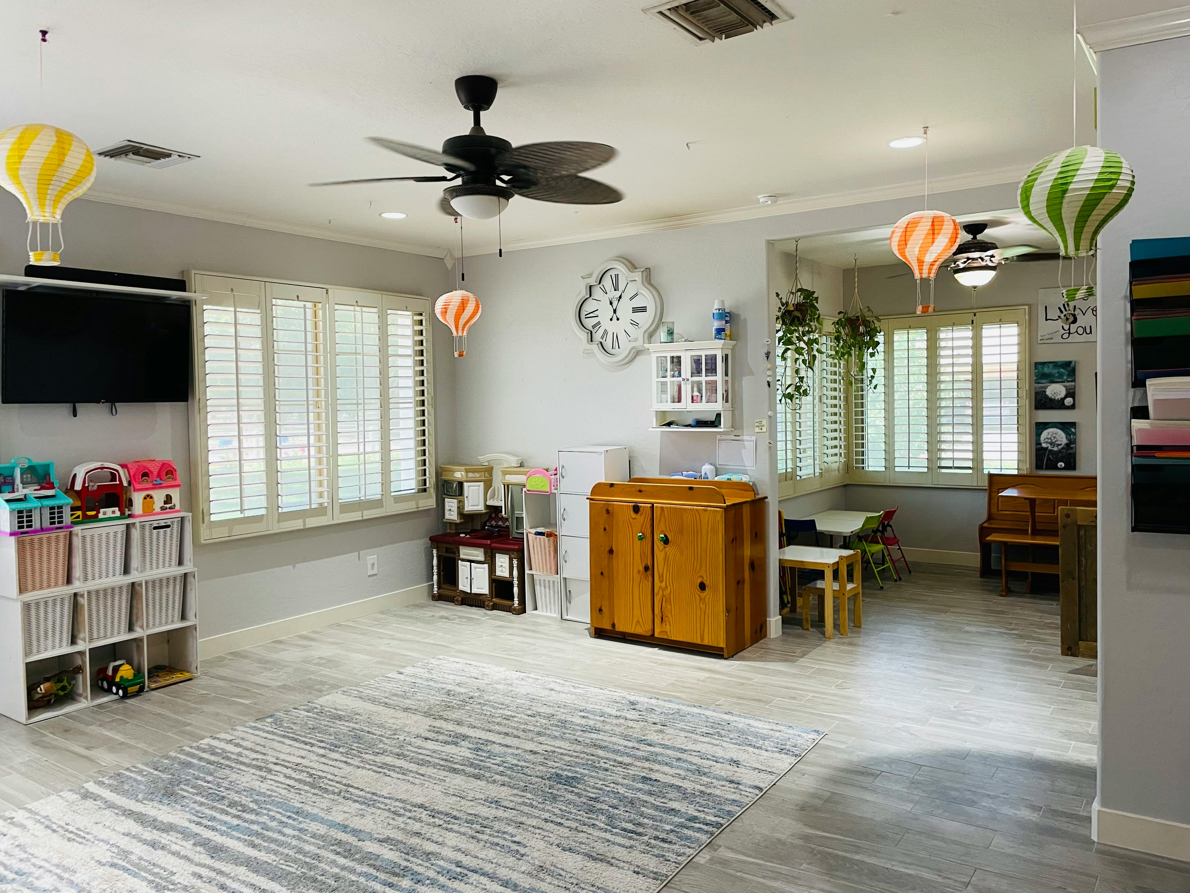 A room with a ceiling fan, windows with blinds, and various furniture