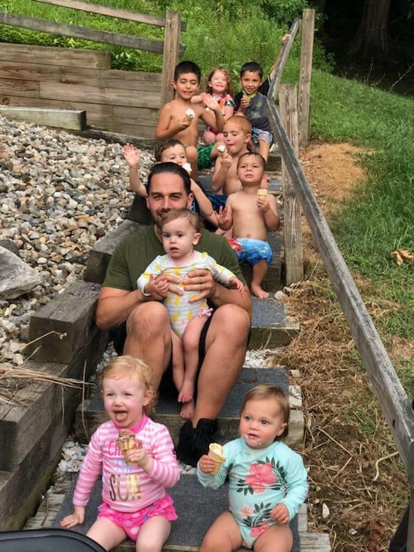 Person sitting on steps with multiple children holding ice cream cones