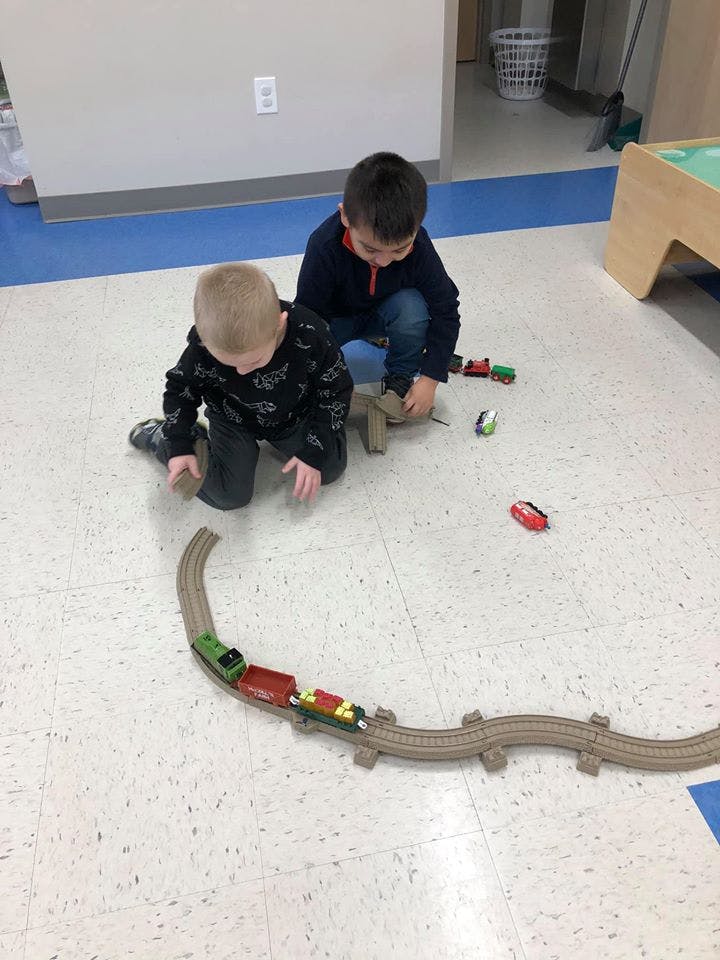 Two children playing with a toy train set on the floor