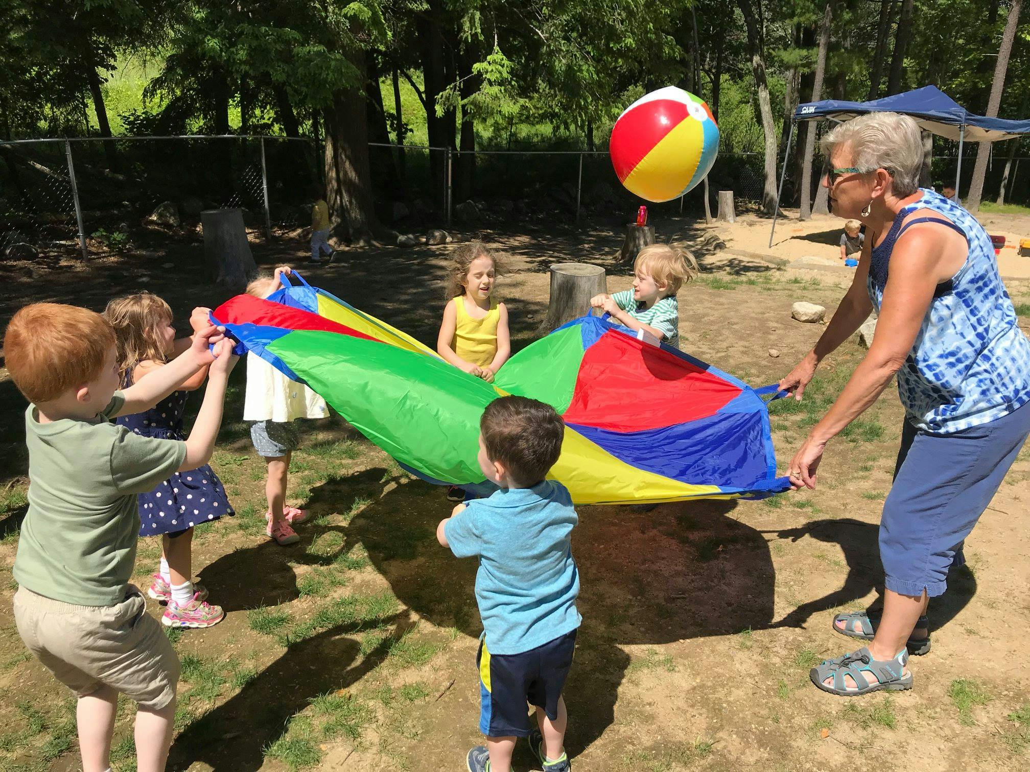 Adult and children playing with a colorful parachute and beach ball