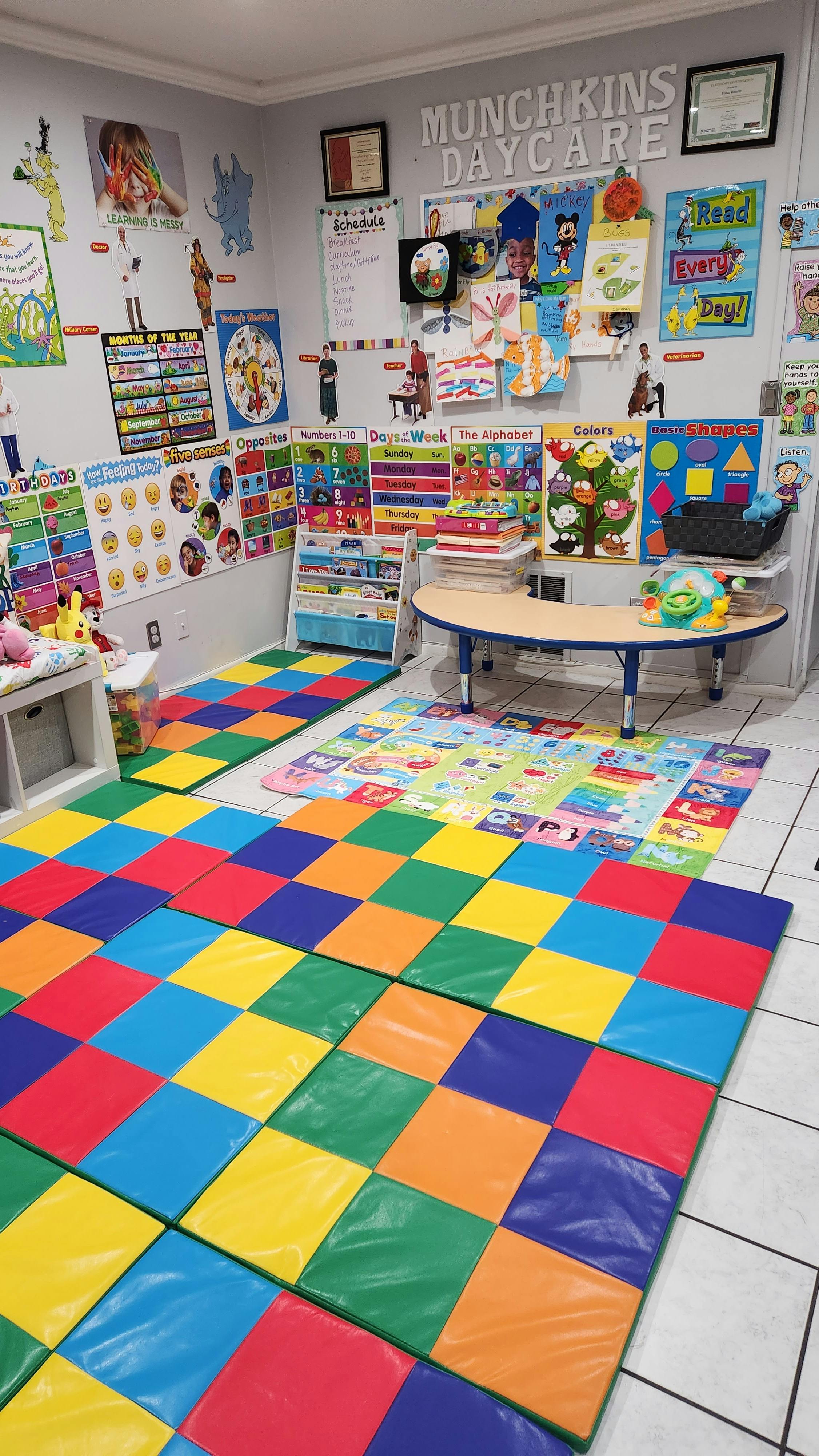 Daycare classroom with colorful floor mats, tables, and educational posters