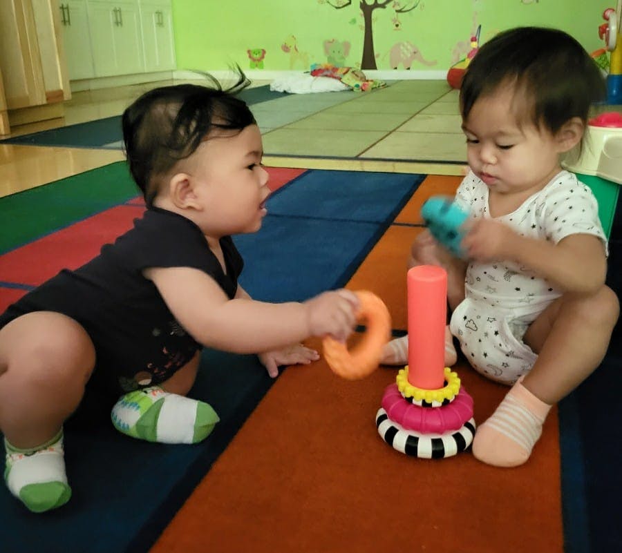 Two children playing with stacking toys on a colorful mat