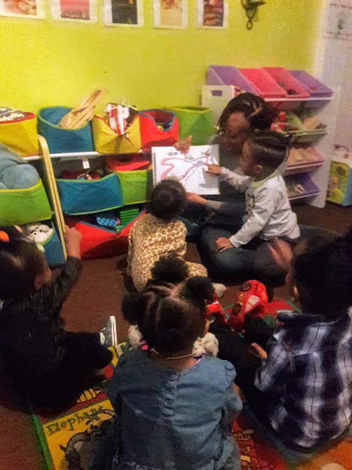 Adult reading a book to several children in a classroom