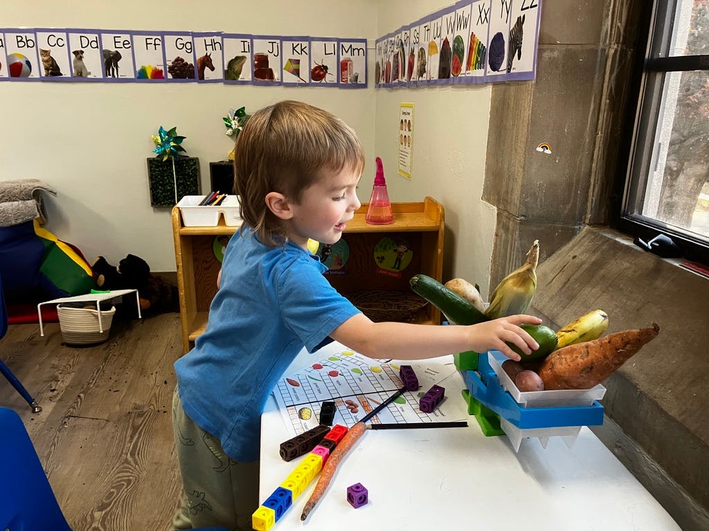 Child reaching for vegetables in a basket on a table