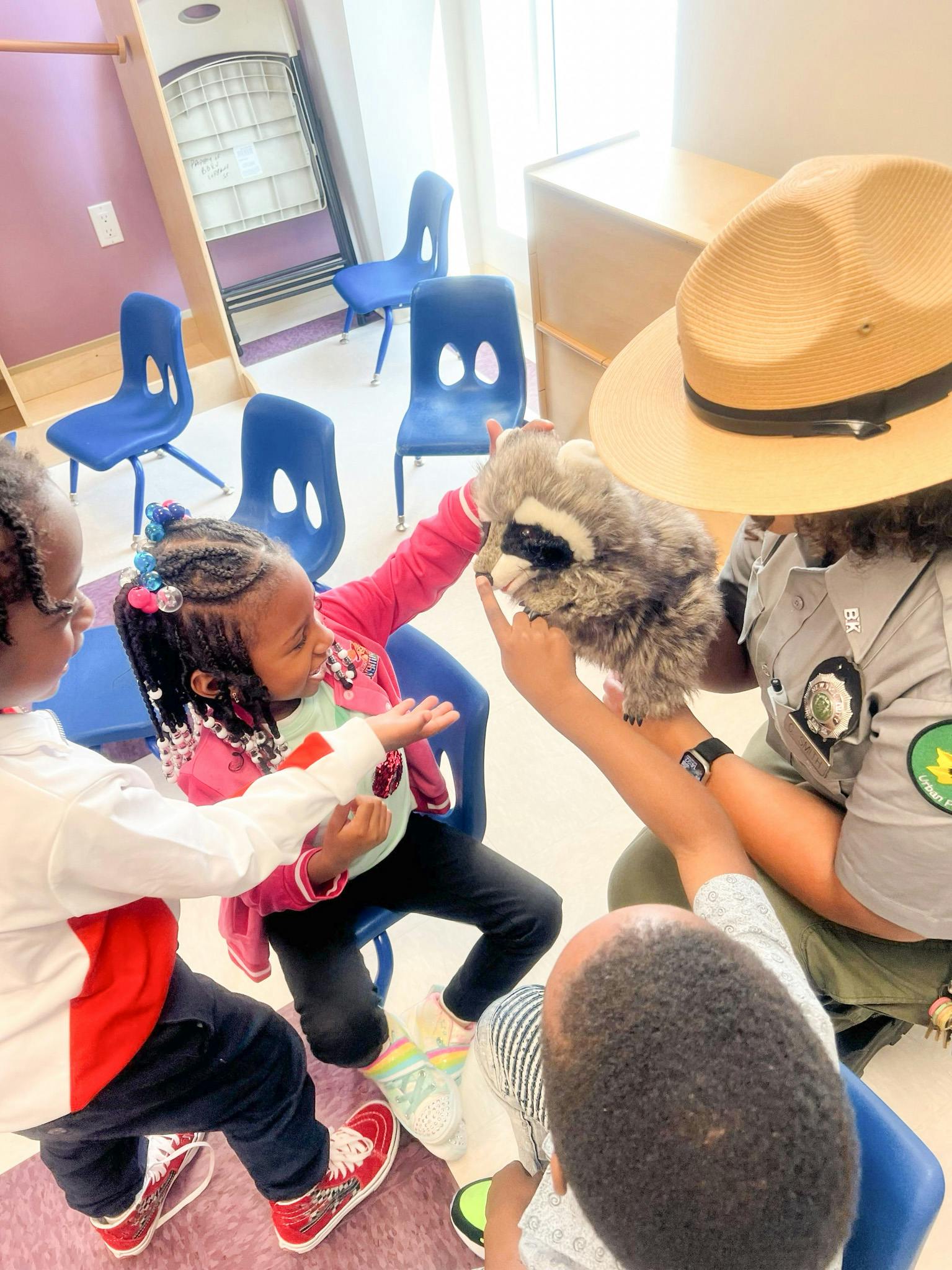 Adult in hat holding a raccoon puppet for children