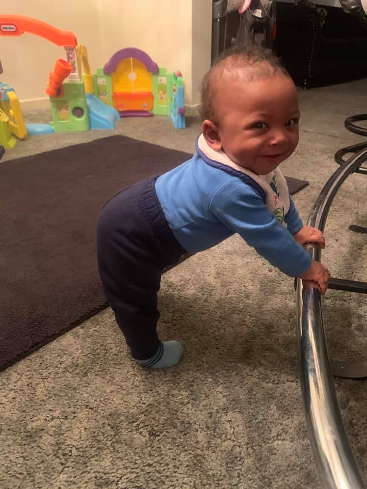 Child standing and holding onto a metal bar