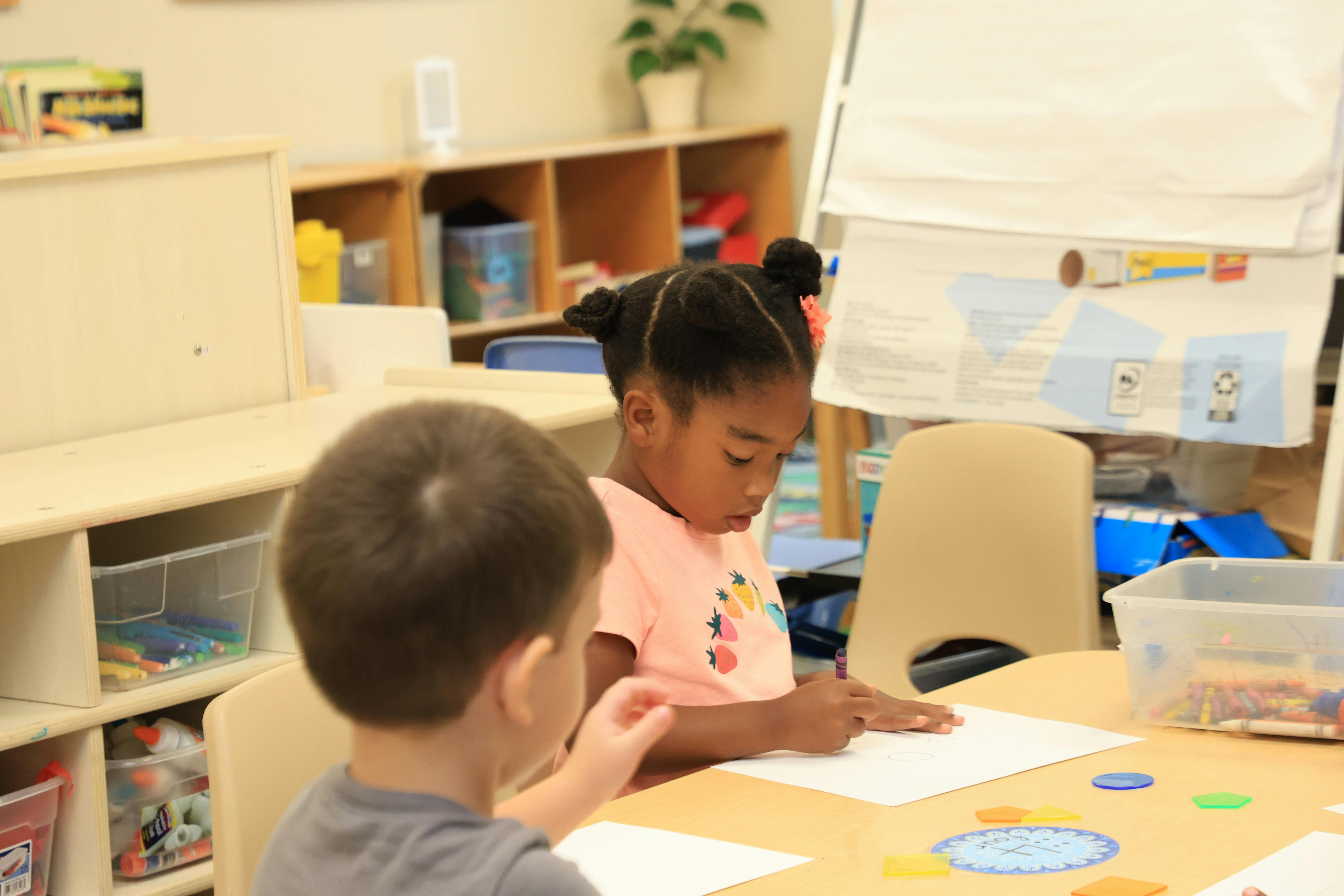 Two children drawing at a table in a classroom