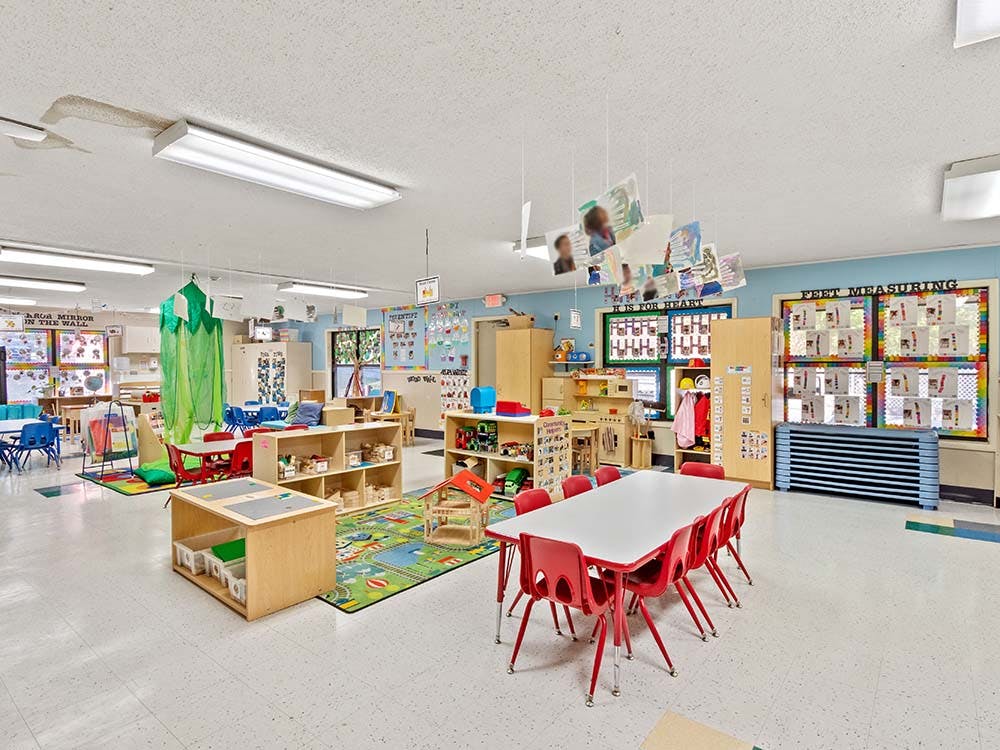 Empty colorful children's classroom with tables, chairs, and learning materials
