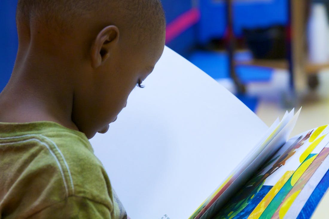 Child looking down at an open book with colorful pages