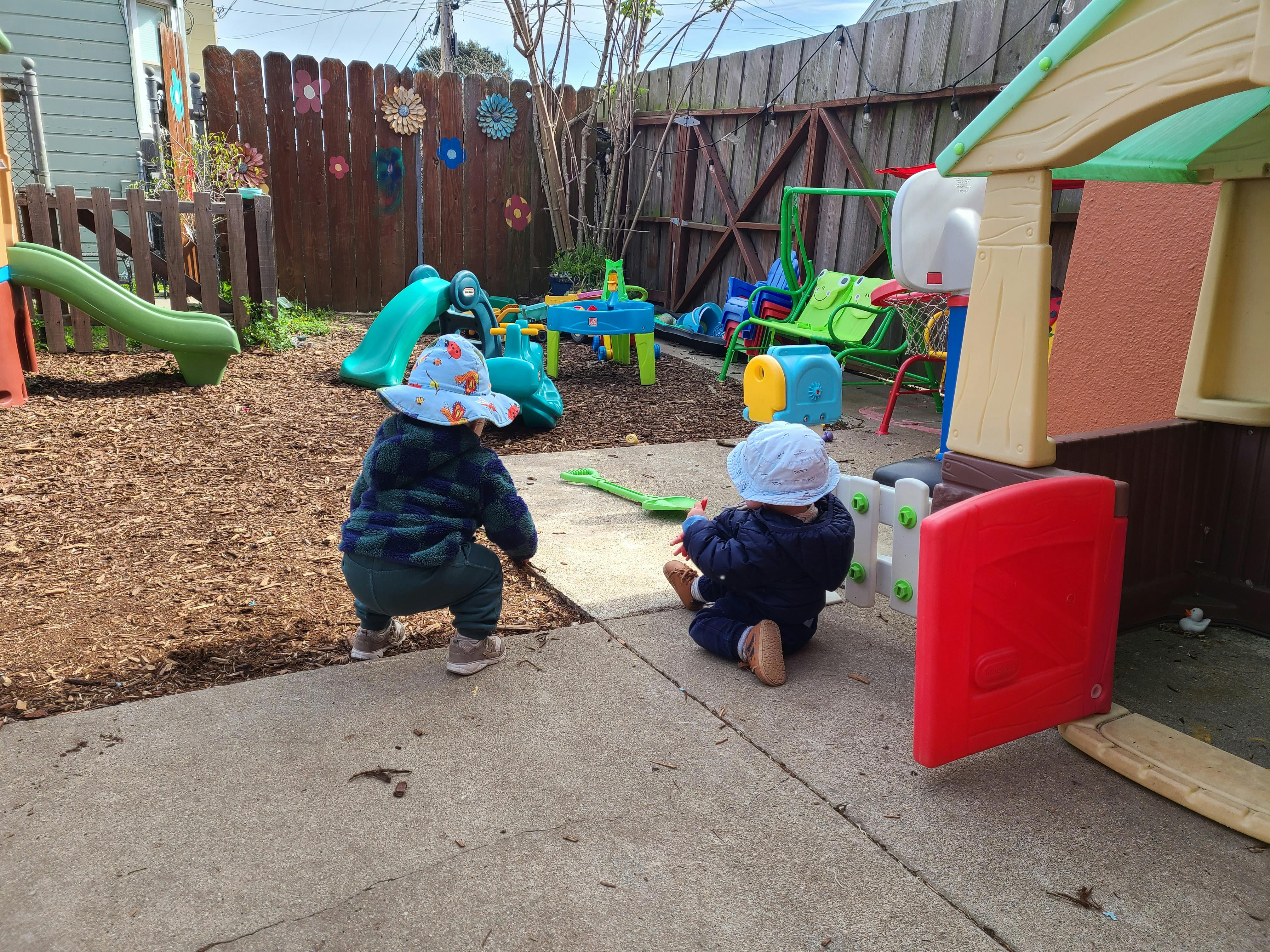 Two children playing in a backyard with play equipment