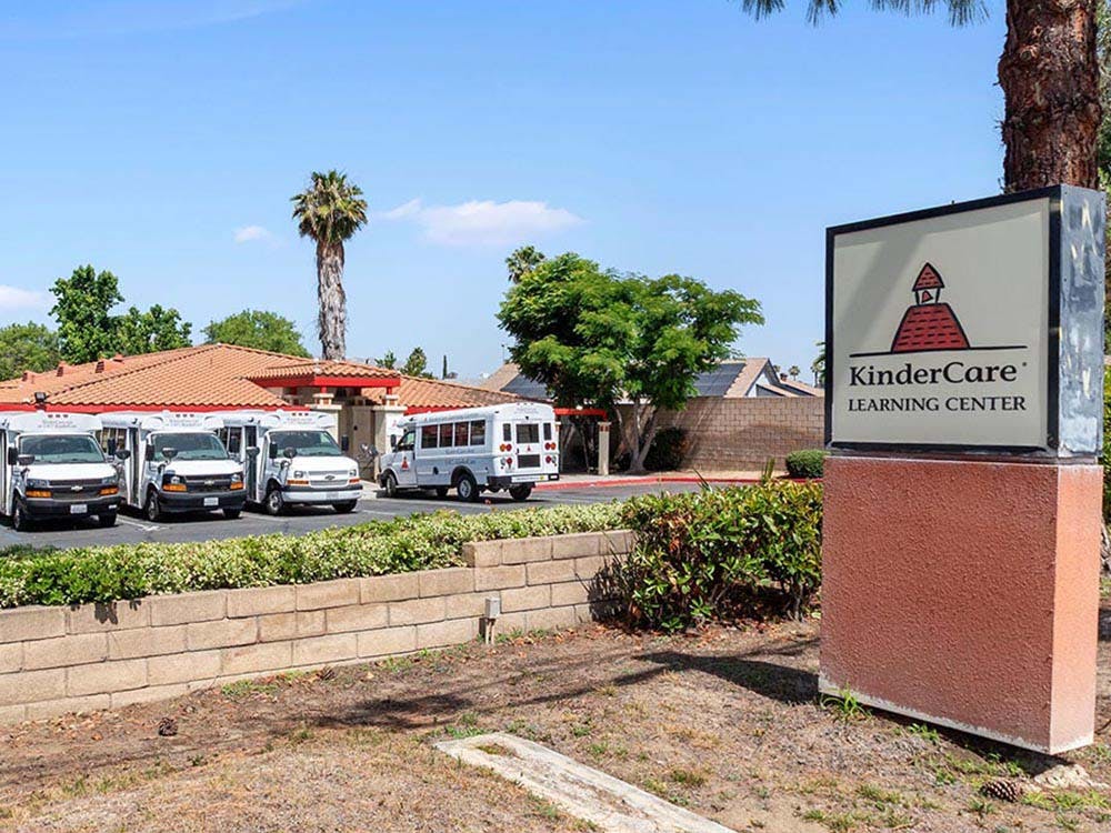 KinderCare Learning Center sign with buses parked outside a building