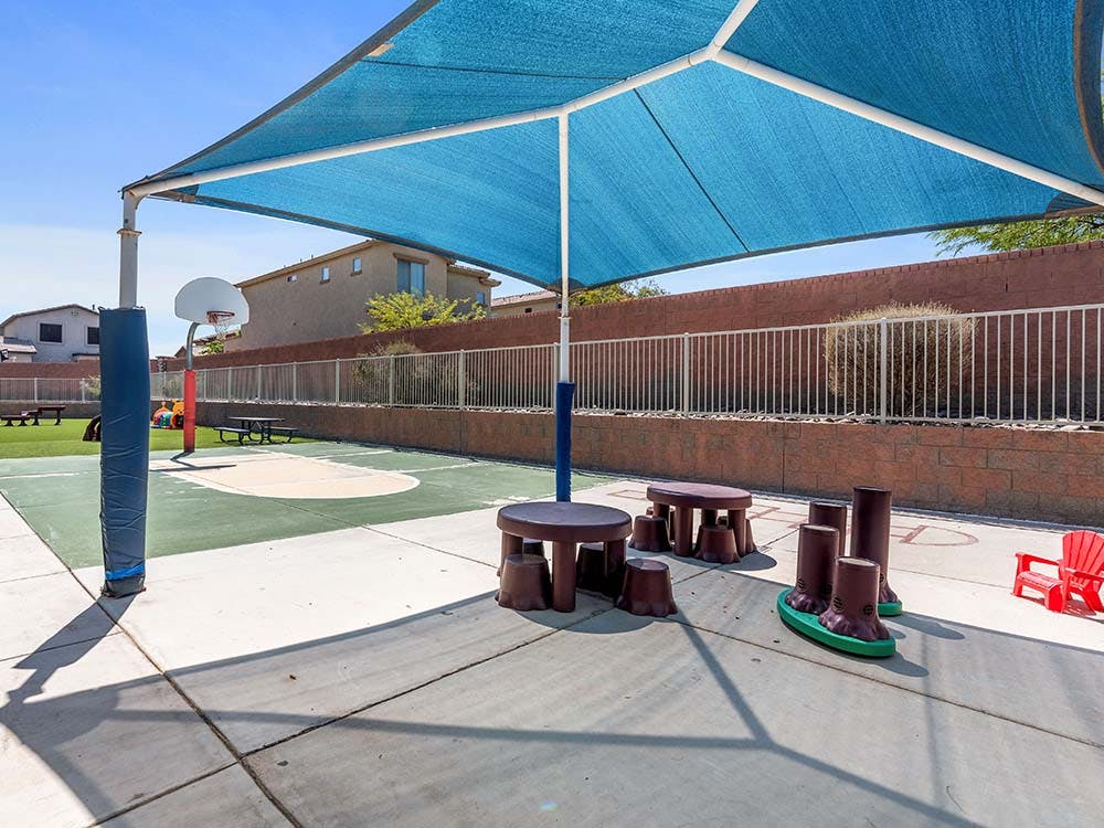Playground area with shade canopy, basketball hoop, and child-sized furniture