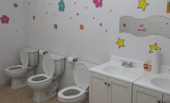 Three small toilets and two sinks in a children's bathroom