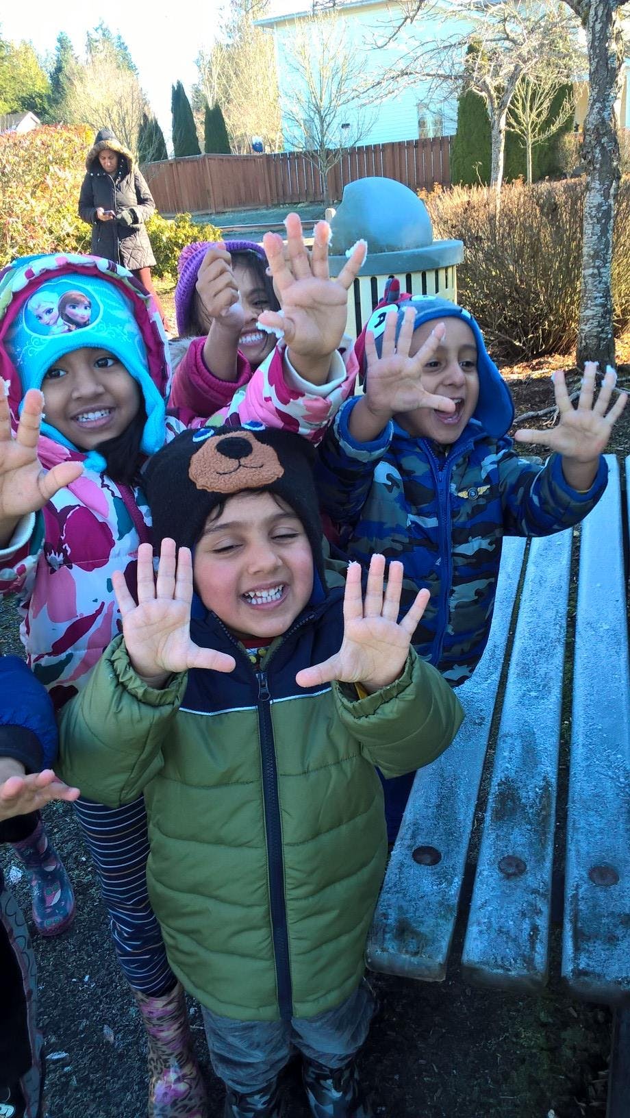 Children in winter clothing raising their hands