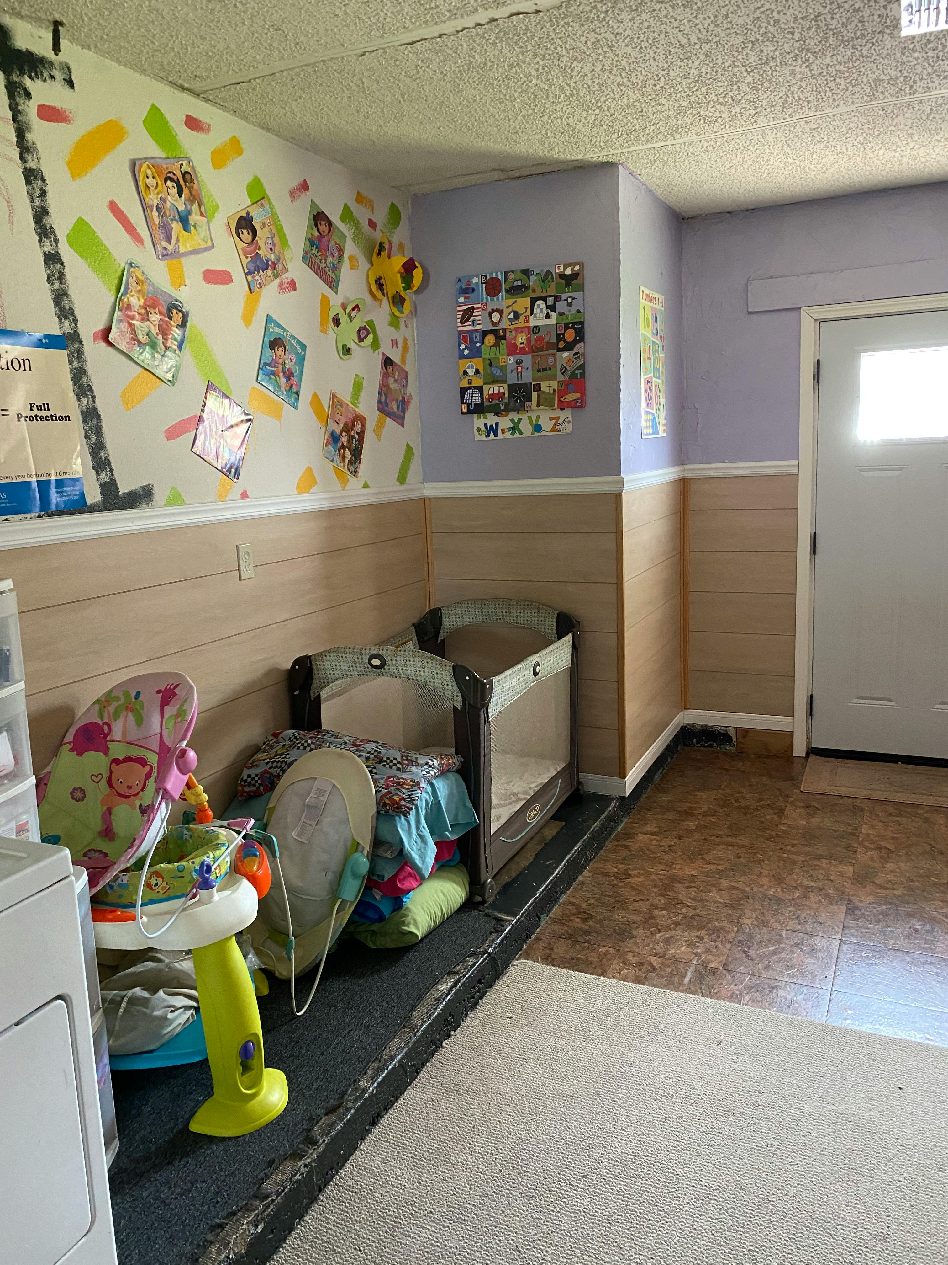Nursery room with a crib, baby bouncer, and colorful wall decorations