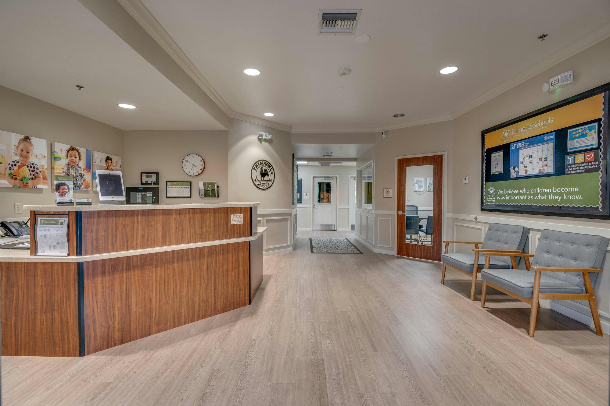 Reception area with a wooden desk, chairs, and a large display on-wall display