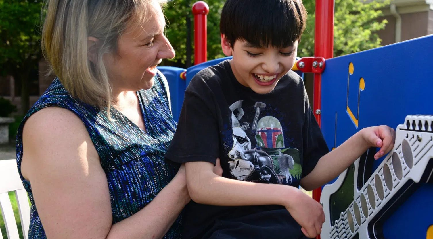 Person and child playing with a toy guitar on a playground