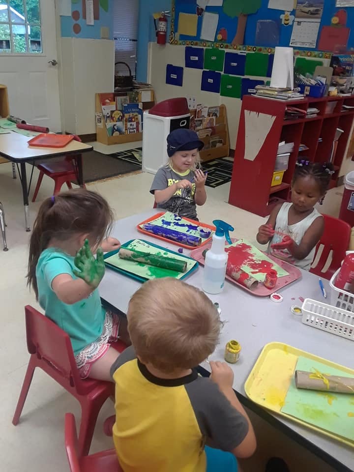 Children painting at a table in a classroom