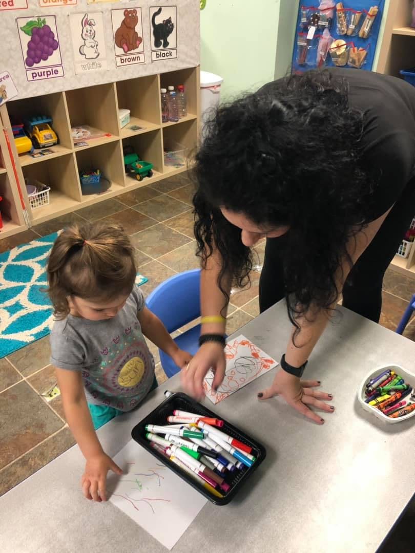 Adult and child drawing at a table in a classroom