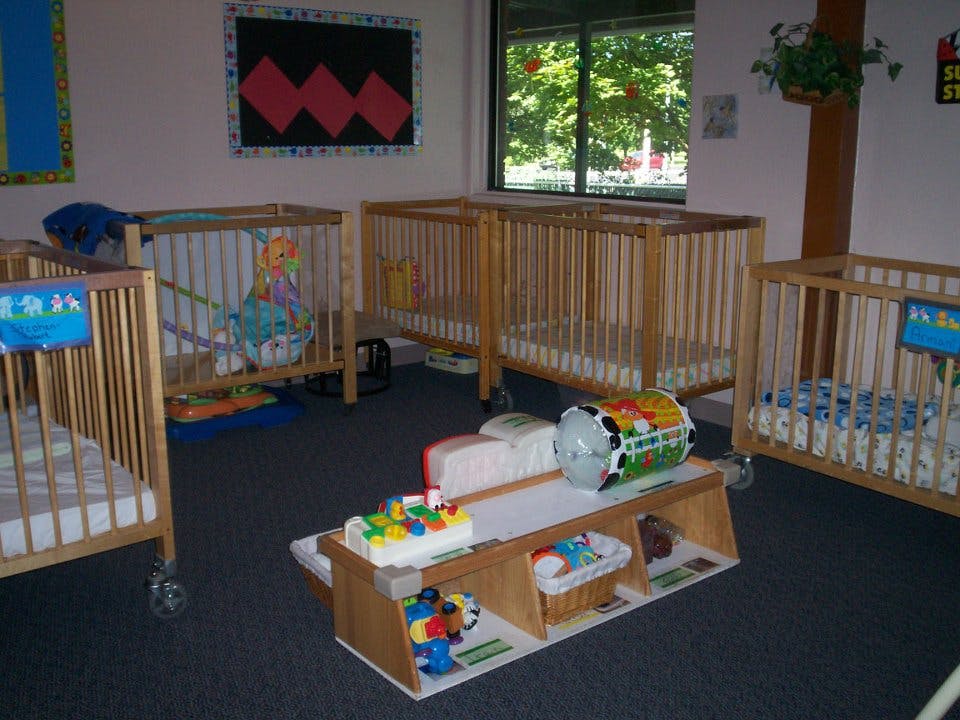 Multiple cribs in a room with a window and toys