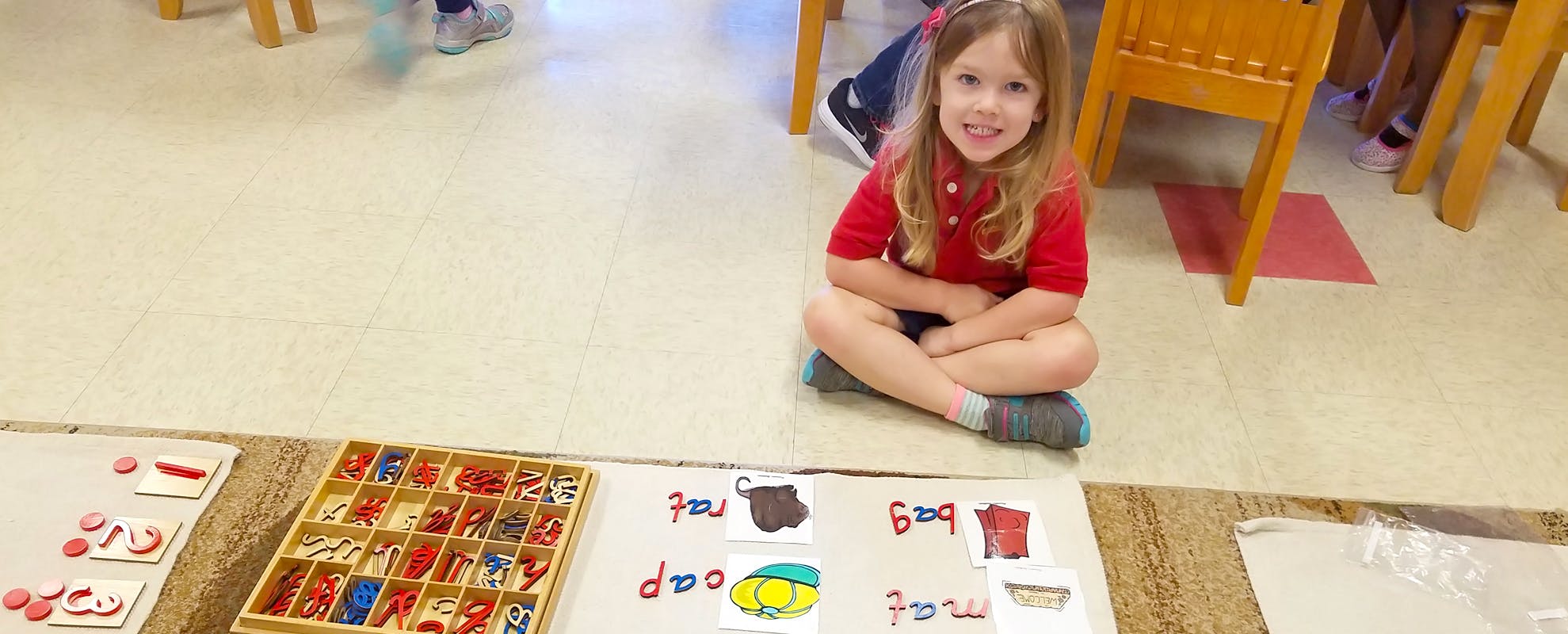 Child sitting on floor with educational materials